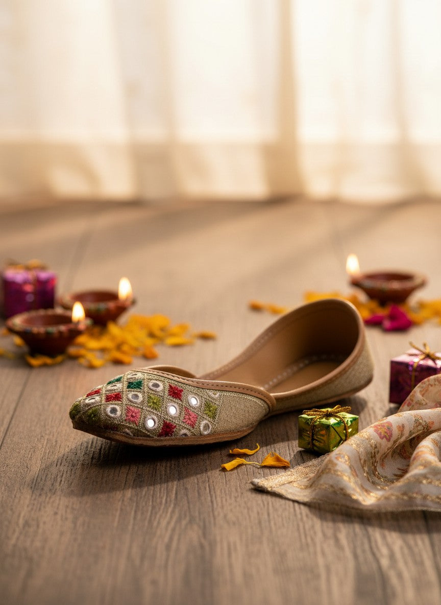 Ujaala beige jutti with embroidered diamond pattern in red, green, and white, featuring mirror work.
