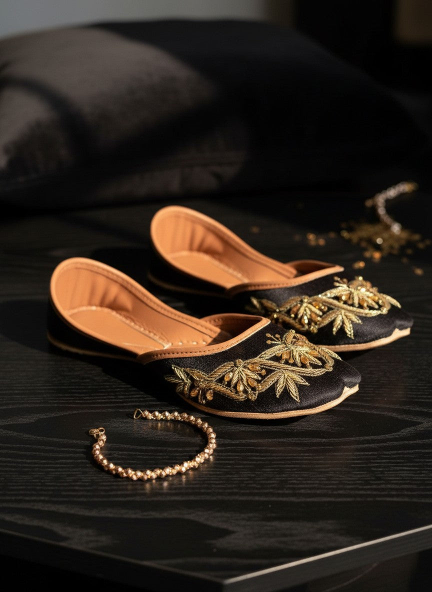 Ujaala black juttis with intricate gold embroidery and beadwork, featuring a tan leather sole.