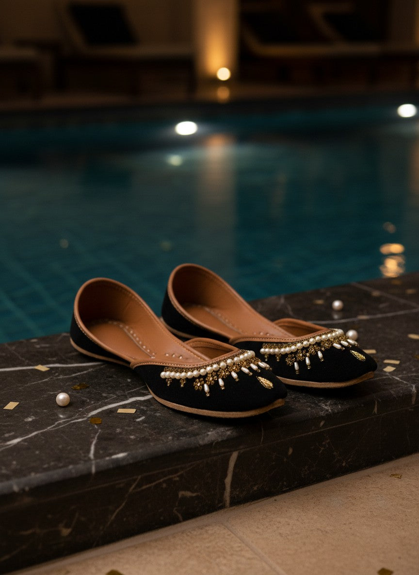 Ujaala Shehnoor black jutti with pearl and gold embellishments, featuring a pointed toe and comfortable flat sole.