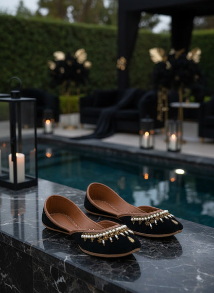 Ujaala Shehnoor black jutti with pearl and gold embellishments, featuring a pointed toe and comfortable flat sole.