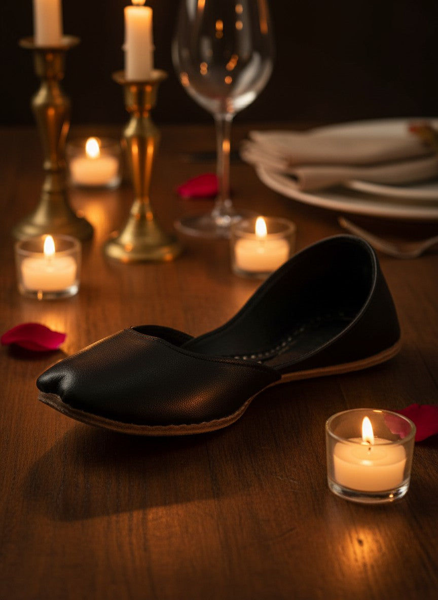 Ujaala Noora black plain leather jutti with a pointed toe and comfortable slip-on design.