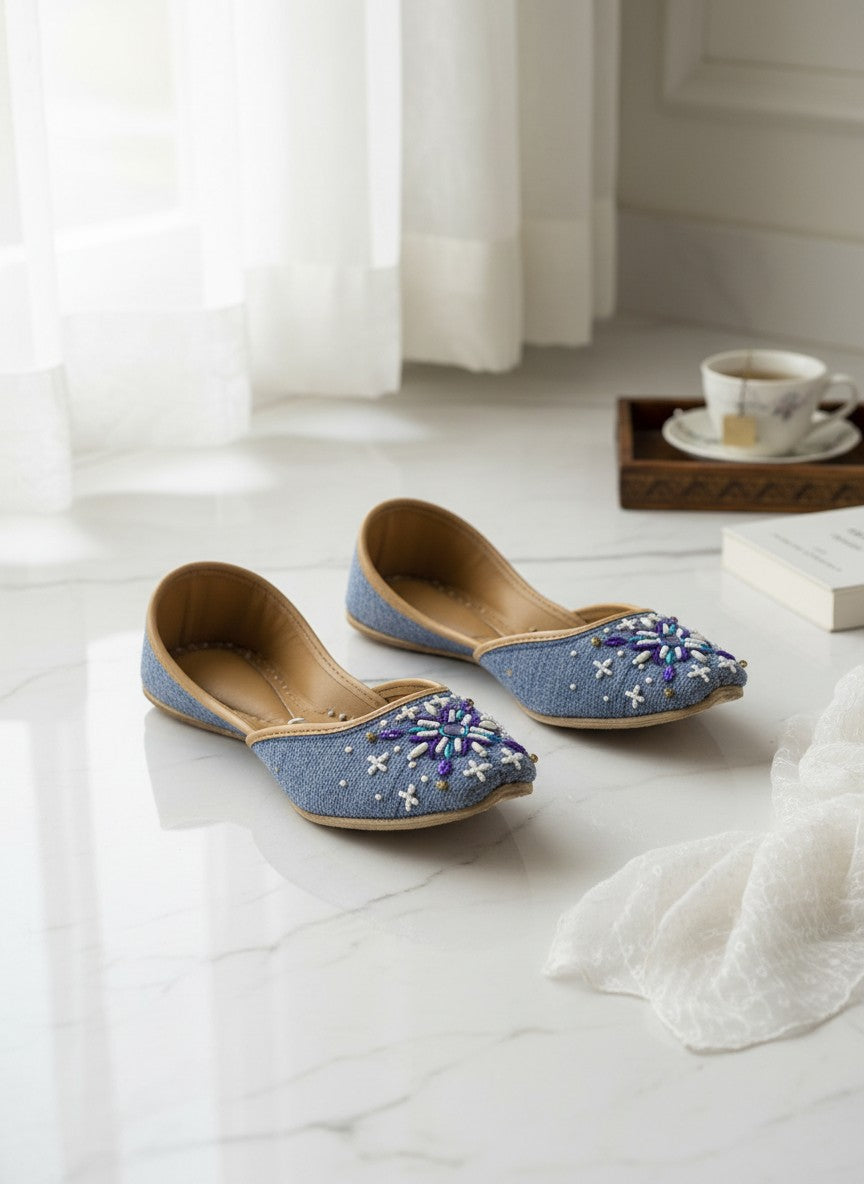 Ujaala Sathi blue denim-textured jutti with white, violet, and blue hand embroidery and bead details.