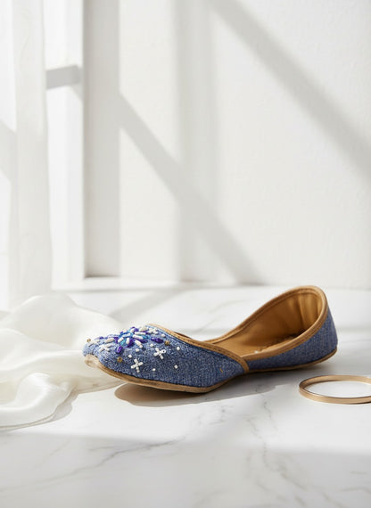 Ujaala Sathi blue denim-textured jutti with white, violet, and blue hand embroidery. Casual chic footwear.