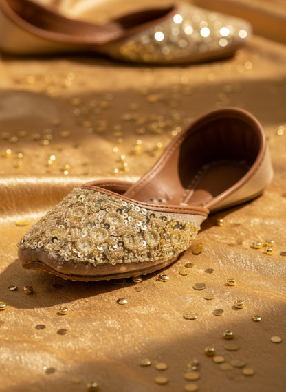 Ujaala gold jutti adorned with circular sequins and beads, featuring a pointed toe and tan leather lining.