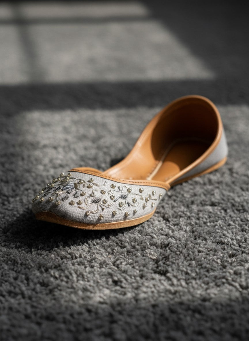 Ujaala Riwa gray jutti with intricate silver floral embroidery and bead embellishments.