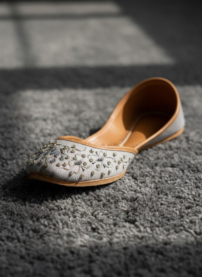 Ujaala Riwa gray jutti with intricate silver floral embroidery and bead embellishments.
