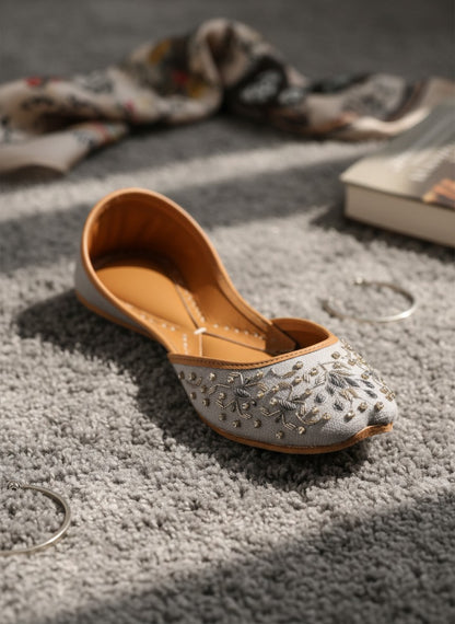 Ujaala Riwa gray jutti with intricate silver floral embroidery and bead embellishments.