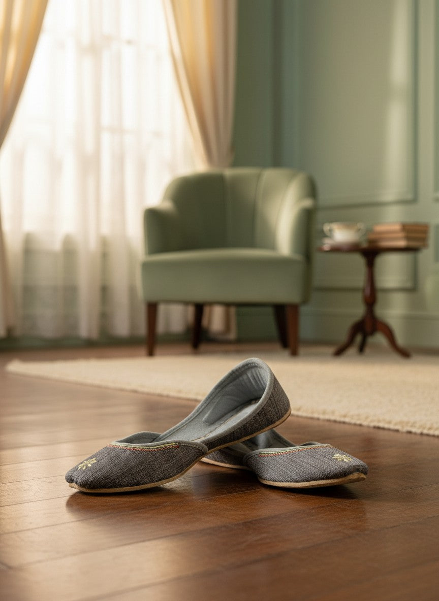 Ujaala grey jutti with embroidered flower detail and decorative trim. Handcrafted for comfort and elegance.