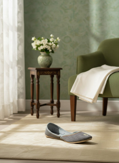 Ujaala grey jutti with embroidered flower detail and decorative trim. Handcrafted for comfort.