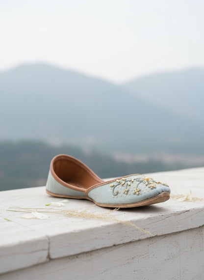 Ujaala Aasmaan pastel blue jutti with gold embroidery and pearl accents, perfect for festive occasions.