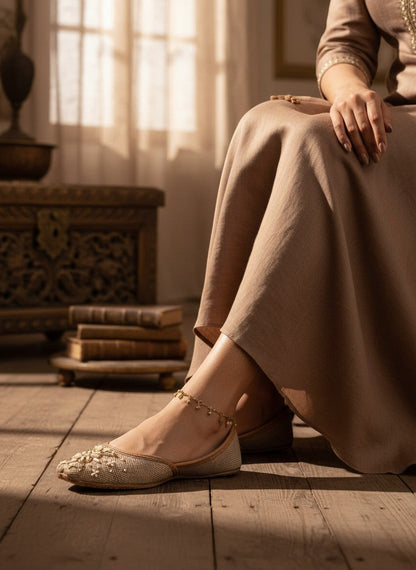 Ujaala Ghazal sand beige jutti with intricate ivory and bronze beadwork and a central gemstone accent.