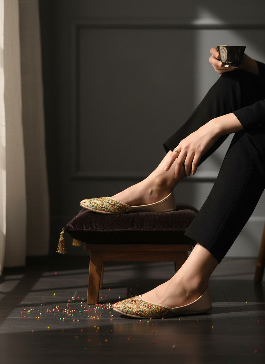 Ujaala Shahi beige jutti with intricate gold embroidery and colourful accents. Traditional flat shoe for women.