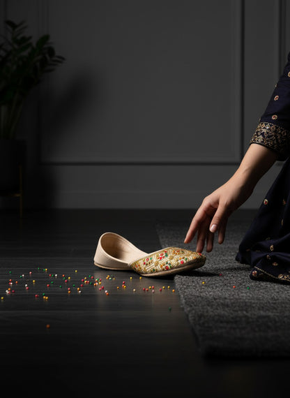 Ujaala Shahi beige jutti with intricate gold embroidery and colorful accents. Traditional flat shoe for women.
