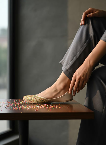 Ujaala Shahi beige jutti with gold embroidery and colourful accents. Traditional flat shoe for women.