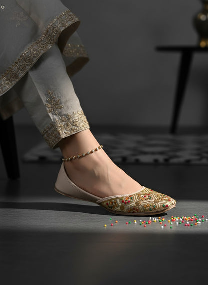 Ujaala Shahi beige jutti with intricate gold embroidery and colourful accents. Traditional flat shoe for women.