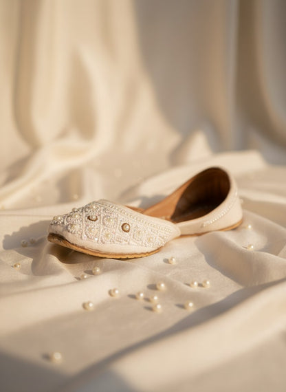 Ujaala Nayaab white jutti embellished with pearls and intricate beadwork. Traditional flat shoe for women.